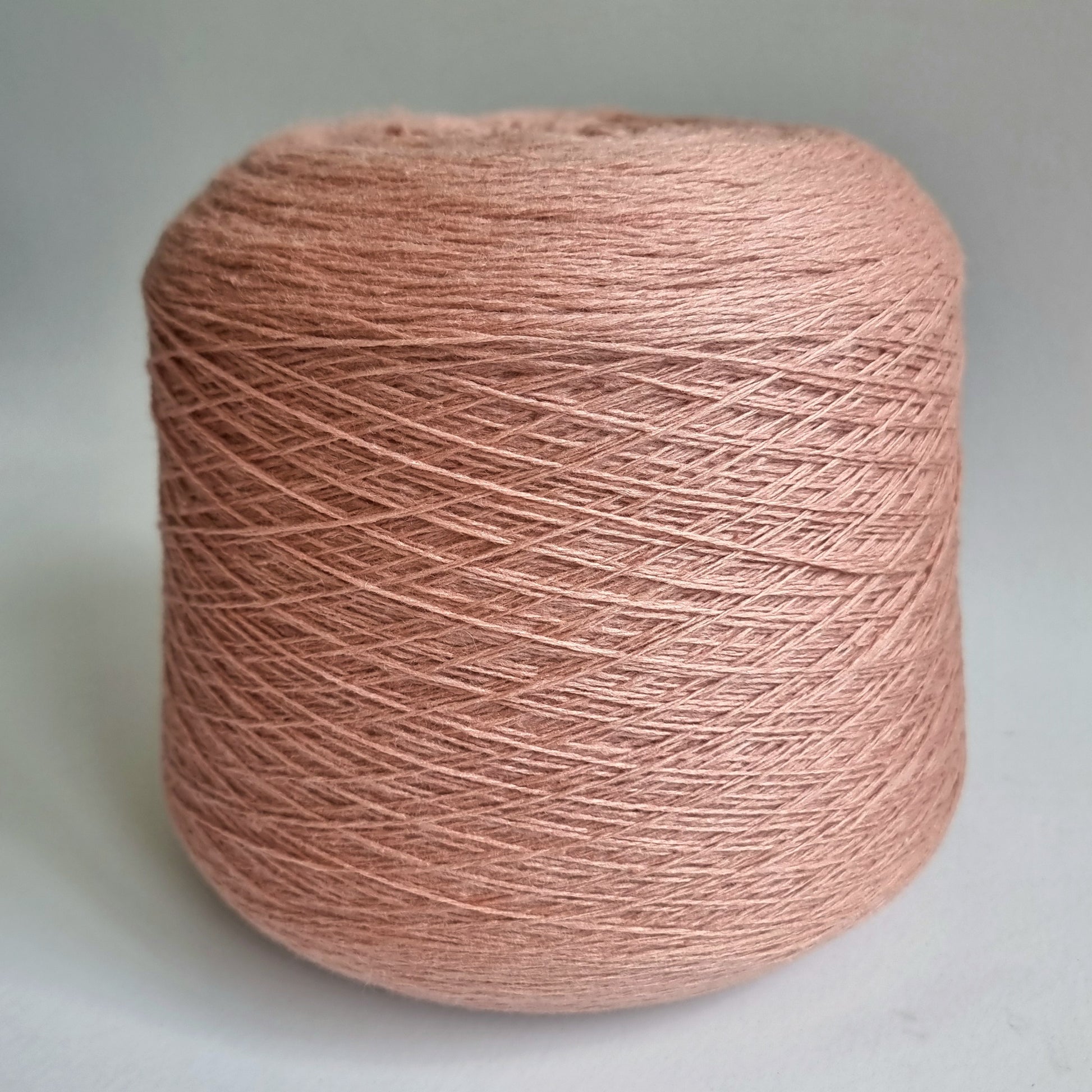 Spool of pink yarn on a light gray background